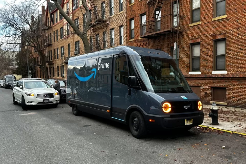 Rivian electric Amazon delivery van delivering packages curbside on New York City street